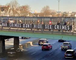 Bridge banner reads war crimes dont hide sex crimes